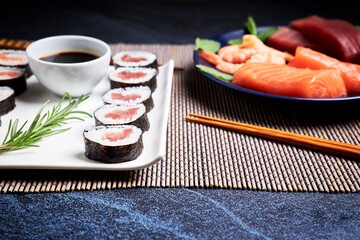 Plate with salmon, tuna and shrimps next to a delicious sushi plate. Oriental food concept