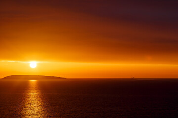 Sunset over the Irish Sea from Penmaenmawr, Wales with a silhouette containers ship on the horizon. Concept is Peace and serenity