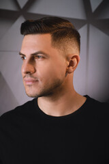 Fototapeta premium Handsome man with trendy hairstyle near dark wall