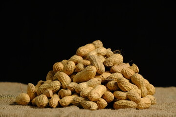 Pile of peanuts on the wicker with side light front of black background