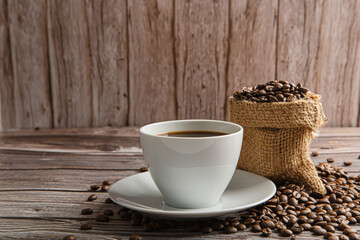Cup of coffee and coffee beans on old wooden background