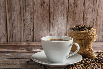 Cup of coffee and coffee beans on old wooden background