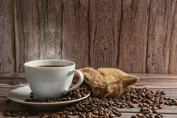 Cup of coffee and coffee beans on old wooden background