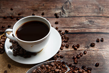 Cup of coffee and coffee beans on old wooden background