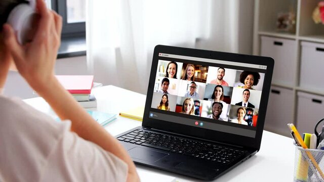 education, online school and distant learning concept - student woman in headphones with laptop computer having video conference at home
