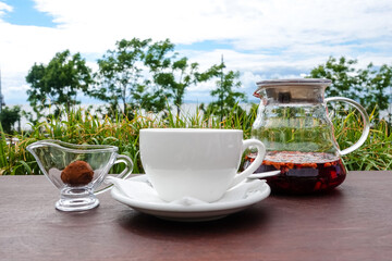 Cup of tea, tea pitcher, and chocolate on a table on an outside cafe terrace