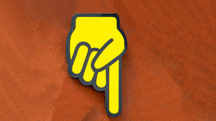 a yellow index finger sign on a concrete wall shows the direction