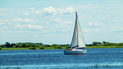 a large white yacht floats upstream on a sunny day