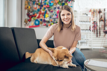 Female pet owner sitting on a sofa with her dog