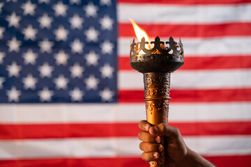 Close up of hands holding Olympic flame torch with US or American flag as background