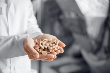 Mill worker holds wheat bran in background of equipment of plant. Industry food factory