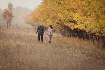 Obraz na płótnie Canvas couple on autumn walk outdoors. Two lovers are hugging in autumn garden. Love and tender touch. Foggy cloudy day filled with the warmth of love. Beautiful autumn landscape for romantic date. 