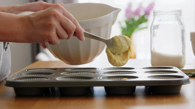 culinary, bake and people concept - happy smiling young woman cooking food on kitchen at home putting batter in baking dish for cupcakes