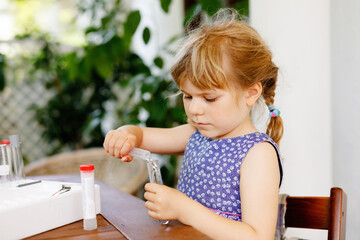Little preschool girl doing chemical experiment in laboratory at school. Toddler child study dropping liquid to test tube , caucasian , biochemistry . chemistry class. Summer school activity