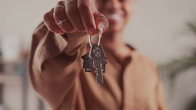 Close up of dark skinned female tenant renter show praise house keys moving to first own new apartment or house, happy woman owner buy purchase home relocate to dwelling rental rent ownership concept.