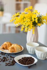 Coffee, croissants and yellow flowers in vase in the kitchen. Breakfast, home, coffee time concept