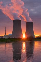 Nuclear power plant against sky by the river at sunset