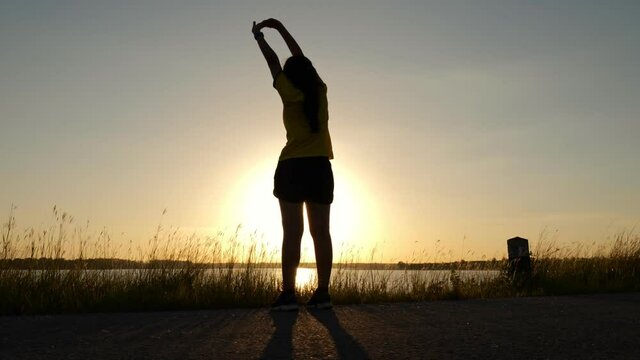 Young  woman streaching before active exercise with sunset background