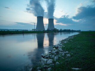 Nuclear power plant against sky by the river at sunset