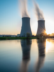 Nuclear power plant against sky by the river at sunset