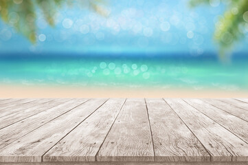 wooden table top summer time tropical blurry seascape with blurry palm leaves and bokeh against...