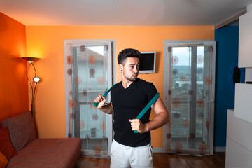 Fototapeta na wymiar Young caucasian man doing exercise stretching a rope at home