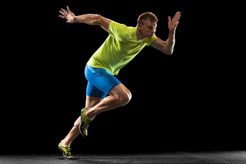 Caucasian professional male athlete, runner training isolated on black studio background. Muscular, sportive man. Concept of action, motion, youth, healthy lifestyle. Copyspace for ad.