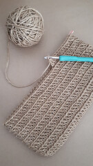 Top view of a crotchet fabric with a needle and a roll of yarn