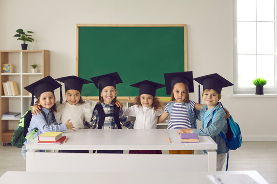 Portrait of a group of cute little graduates of kindergarten or junior class in bachelor hat or mortarboard. Concept of childhood, school, education, knowledge, graduation and people.