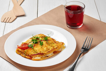 French omelet with cheese and vegetables with berry juice
