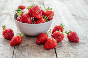 Red juicy strawberries in a bowl on wooden table, summer fruits containing antioxidants, vitamin C,...