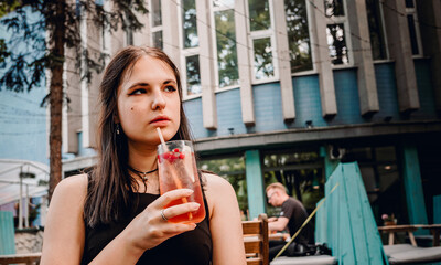 young teenager girl holding glass with a lemonade cocktail and drink in oudoor cafe