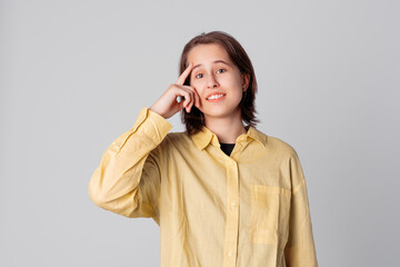 Confident teen girl pointing with finger at head, dressing in stylish yellow shirt. Concept of thinking. Be smart and think