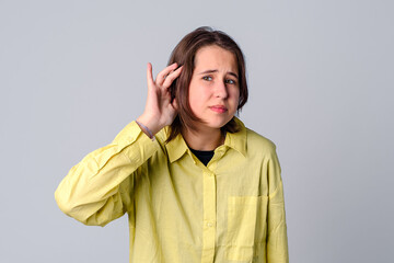 curious teen girl putting her hand to ear and listens. The concept of secrecy, rumors, gossip,...