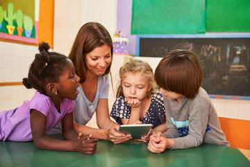 Kindergarten teacher and children using tablet computer online