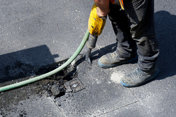 road works on a gas pipeline, prising up the asphalt of a road with a jackhammer to expose a gas...