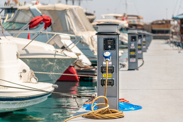 Electrical power sockets bollard on pier near sea coast. Charging station for boats in...