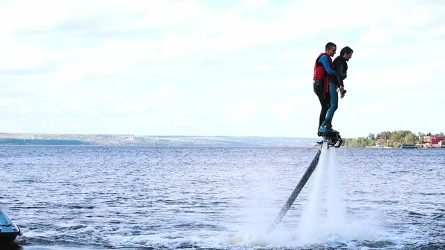 Two men learning how to use flyboards on the river