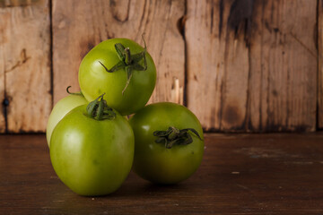 unripe green tomatoes on brown wooden kitchen rustic background. Farmer fresh organic product. Vegan eco-friendly no animal food