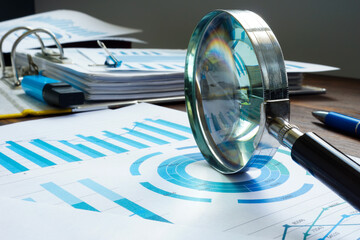 Magnifying glass as symbol of audit and papers.