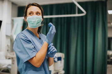 Female nurse with a mask putting on gloves - obrazy, fototapety, plakaty