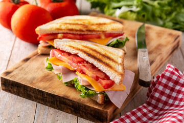 Sandwich with tomato,lettuce,ham and cheese on wooden table	