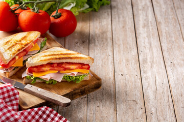 Sandwich with tomato,lettuce,ham and cheese on wooden table. Copy space