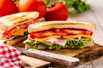 Sandwich with tomato,lettuce,ham and cheese on wooden table	