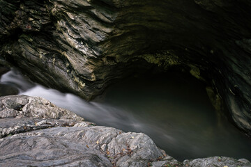 natural small rapid stream flow from waterfall between rocky cliff canyon