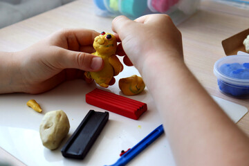 The child plays and builds figures from the play dough. Children's hands with colored plasticine. Development of fine motor skills of fingers in children