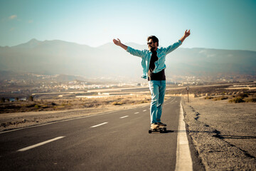 Fototapeta na wymiar Adult young man moving on long board table on a long street asphalt road and outdoors mountains in background - concept of freedom and active people