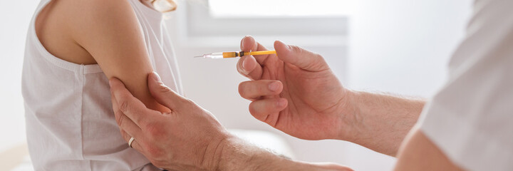 Close-up of a sweet blond boy and a doctor with a syringe