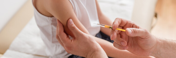 Close-up of a sweet blond boy and a doctor with a syringe