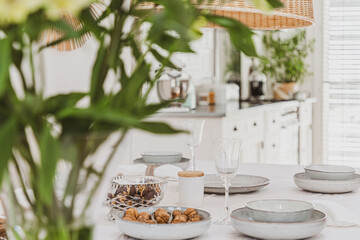 Plates, vine glasses, nuts and green flowers on the table in stylish kitchen